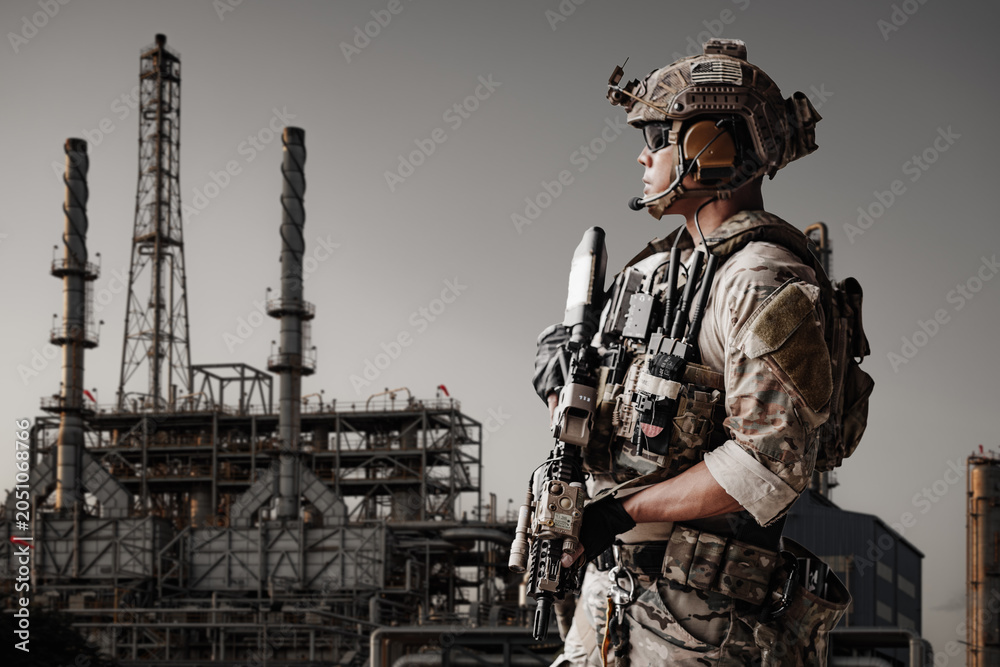 Fototapeta premium Soldier stands at Gas Oil Refinery industrial facility in a military Energy operation security.