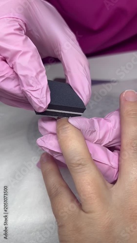 Manicure. Close-up of a girl's fingers and nails during a manicure. Filing her nails with a nail file.