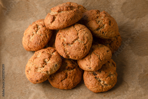 A top-down view shows golden-brown oatmeal cookies with cracked, rustic surfaces arranged neatly on parchment paper, evoking a warm, homemade feel.