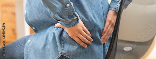 Foto Close-up woman massaging her lower back has back pain because of sitting posture during work in office