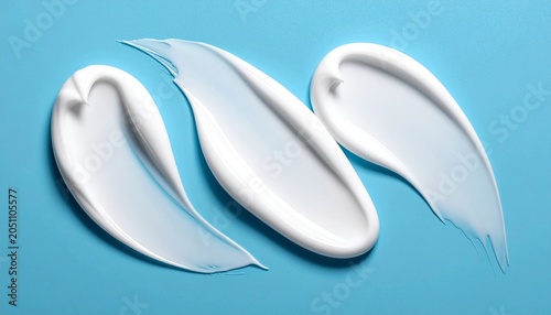 Three Swirls of White Cream on a Blue Background.