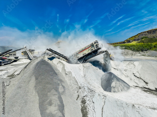 Photos Granite quarry workers operate heavy machinery to extract stone during sunny day