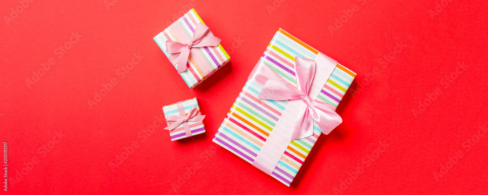Fototapeta premium Gift box with pink bow for Christmas or New Year day on red background, top view