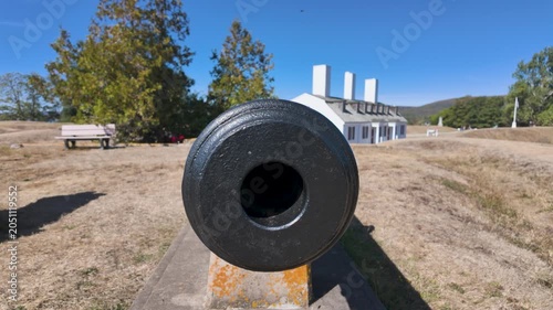Slow motion footage of an historic cannon at Fort Anne National Historic Site in Annapolis Royal Nova Scotia Canada positioned on the earthwork ramparts with preserved military buildings