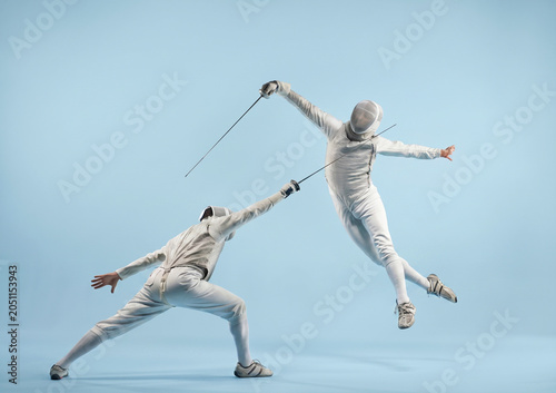 Foto Two fencers in intense duel, one lunging while the other leaps dramatically with foils