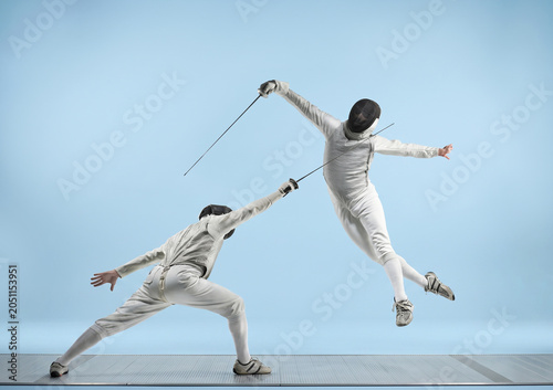 Bild auf Leinwand Two fencers in intense duel, one lunging while the other leaps dramatically with foils