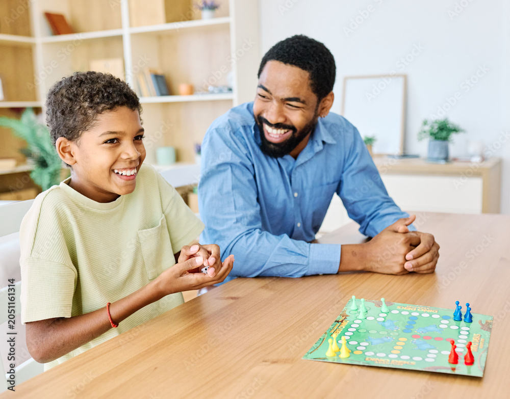 Fototapeta premium Portrait of a happy african american family at home, having fun playing a board game challenge game, playing board game ludo at home