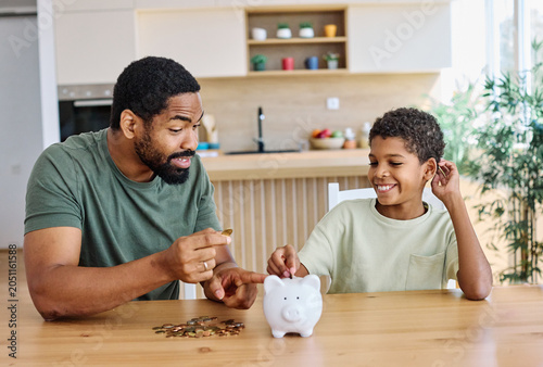 Family father and son putting coin Money in piggybank  at home. Personal savings, Bank safety and financial investments concept
