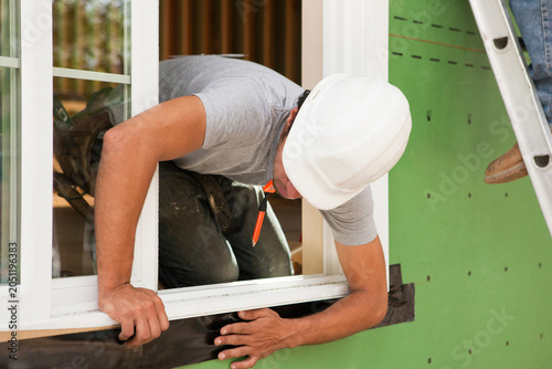 Hispanic carpenter installing flashing around window frame