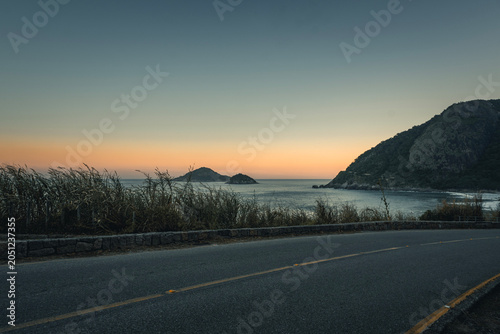 Vista panorâmica do oceano durante o crepúsculo com ilhas ao fundo e tons suaves no céu, Praia de Grumari, Rio de Janeiro