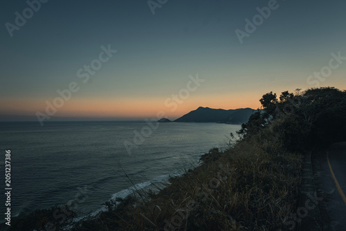 Vista do litoral com oceano calmo, formações insulares e atmosfera tranquila ao entardecer, Praia de Grumari, Rio de Janeiro