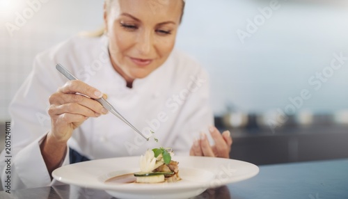 Chef Carefully Plating an Exquisite Dish with Precision and Attention to Detail in a Modern Kitchen Setting