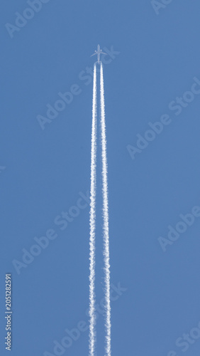 twin engined jet liner aircraft with contrails, in flight at high altitude, clear blue sky