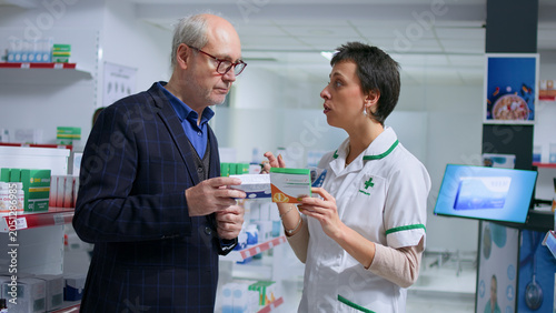 Foto Elderly man feeling unwell visiting chemist shop, looking to find pharmaceutical