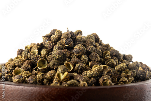 Pile of dried green szechuan peppercorns or chinese prickly ash on white background