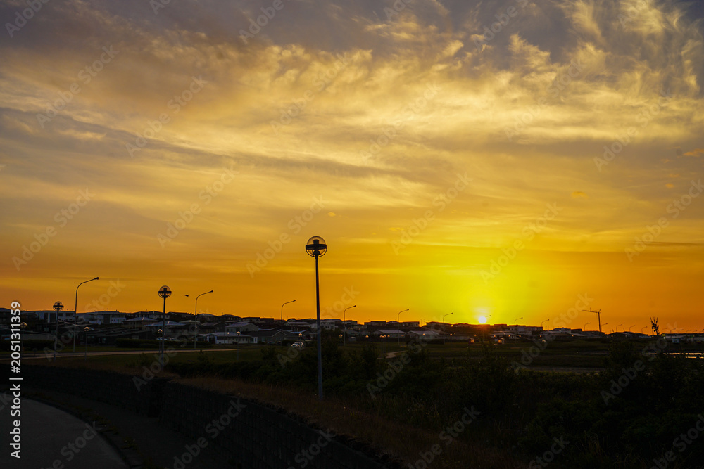 Obraz premium Sunset over a suburban landscape with streetlights and distant buildings,ICELAND