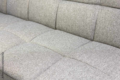 Close-up view of grey textured fabric sofa, minimalist furniture detail.