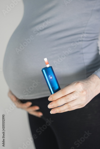 Woman smoking during pregnancy. Danger, unhealthy habit. Vertical photo.