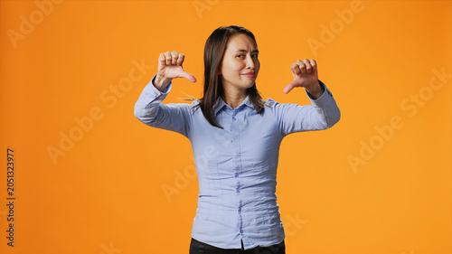 Fotografía Asian person giving thumbs down in front of studio camera, expressing negativity and disapproval with dislike symbol
