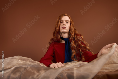 Bilde på lerret Elegant young man with long red hair showcases flawless style and charm in a war