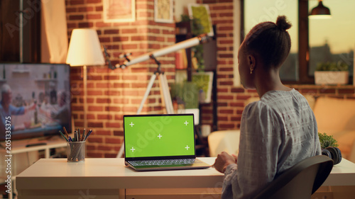 Foto Freelancer on videocall with green screen display, using laptop at home and working on remote job
