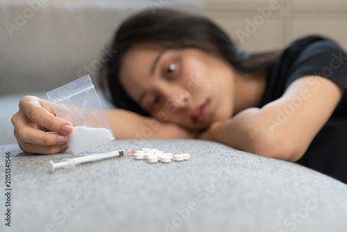 Anti drugs, drug addict asian young woman, girl hand holding heroin or cocaine in plastic bag, use narcotic at home, abuse overdose. Sick pain of health, unhealthy people. Suicide depressed or despair