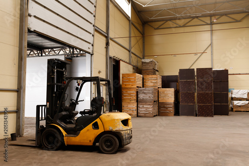 Canvastavla Yellow forklift truck parked inside industrial warehouse next to open gate
