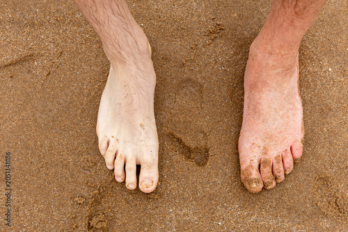 Close-up of a bare foot stepping into soft sand with a visible footprint, showing summer travel and outdoor relaxation