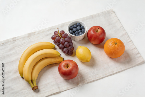 Assorted fresh fruits including bananas, grapes, blueberries, apples, lemon, and orange on a cloth