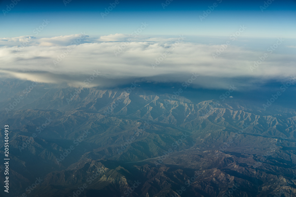 Fototapeta premium Mountains and clouds seen from high altitude during a flight