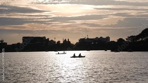 Silhouettes of people rowing boats can be seen at the public pond.