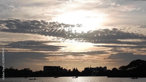 Silhouettes of people rowing boats can be seen at the public pond.