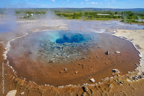 Bild auf Leinwand Aerial view of a steaming geothermal hot spring with vibrant blue water and mine