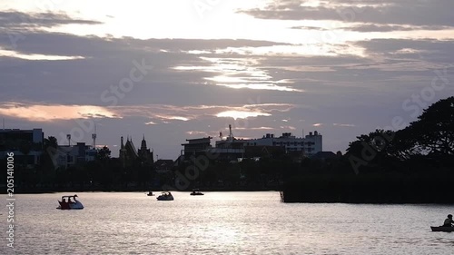 Silhouettes of people rowing boats can be seen at the public pond.