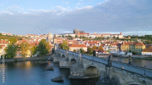 Witness the beauty of Charles Bridge and Prague Castle as the morning sun illuminates the historic buildings and the serene Vltava River flows below. Discover the charm of Czechia.