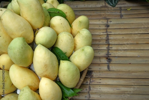 Foto Golden Ripe Mangoes on a Rustic Bamboo Table with Copy Space