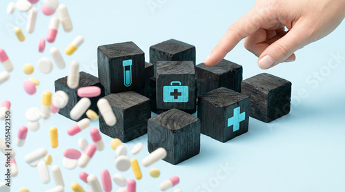 Hand pointing at medical icon blocks with falling capsules