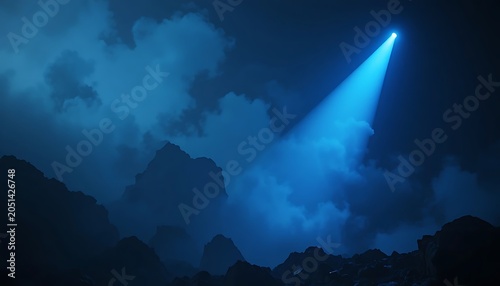Atmospheric night scene featuring a bright blue spotlight shining through dark swirling clouds onto rugged mountain peaks creating a dramatic cinematic and mysterious landscape background.