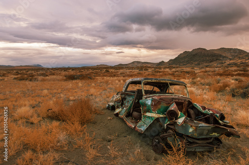 Deteriorated abandoned classic car wreck in the middle of dramatic desert landscape, Nevada, USA