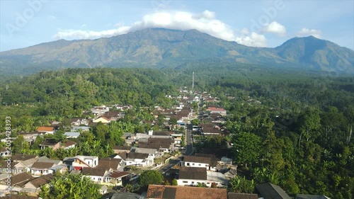 A 4K aerial view of a beautiful village beneath the majestic peak of Mount Arjuna.