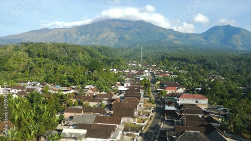 A 4K aerial view of a beautiful village beneath the majestic peak of Mount Arjuna.