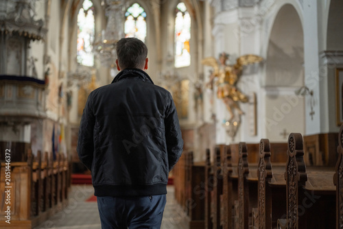 Fotografie Man seeking peace in a church, walking to wooden pew to pray, surrounded by silence and soft natural light