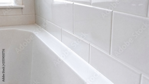 A clean white bathroom with a sealed bathtub and tile joint.