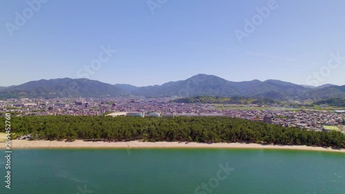 気比の松原（福井県敦賀市）の海と広大な松林、市街地と山並みのパノラマ、左へ横移動するドローン空撮 / Kehi no Matsubara in Tsuruga, Fukui: Panoramic drone aerial of sea, vast pine forest, city and mountains, tracking left