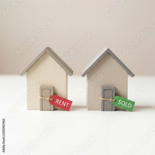 Two miniature houses with rent and sold sign flags real estate concept