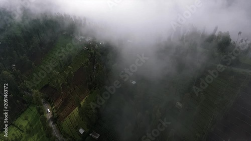 4K top down drone shot of a winding road through misty green terraced fields.