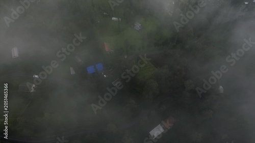 4K top down drone shot of a winding road through misty green terraced fields.