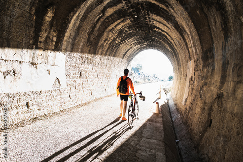 A cyclist walks into the tunnel light pushing his bike during a relaxed ride