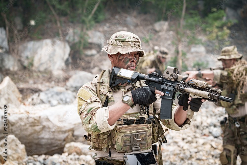 Fototapeta premium Special forces soldier in camouflage gear aiming a rifle during a tactical operation
