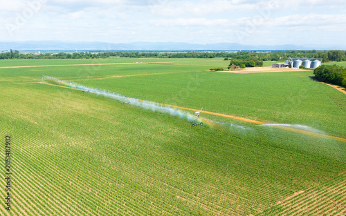 Aerial view of a center pivot irrigation system watering a green agricultural field during the growing season